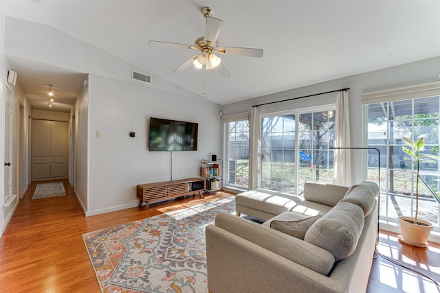 living room featuring light hardwood / wood-style flooring, a wealth of natural light, vaulted ceiling, and ceiling fan