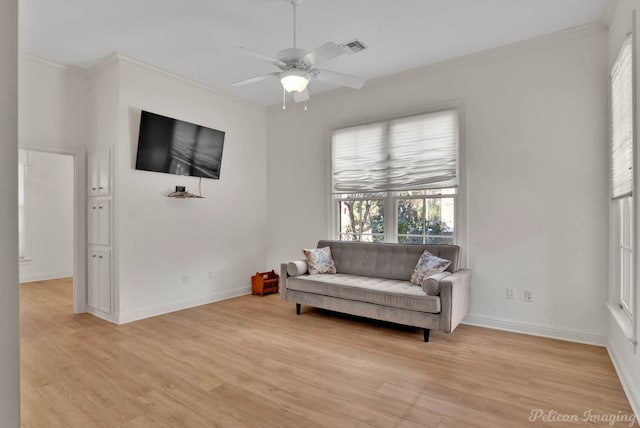 living area featuring light wood-type flooring, ceiling fan, and crown molding