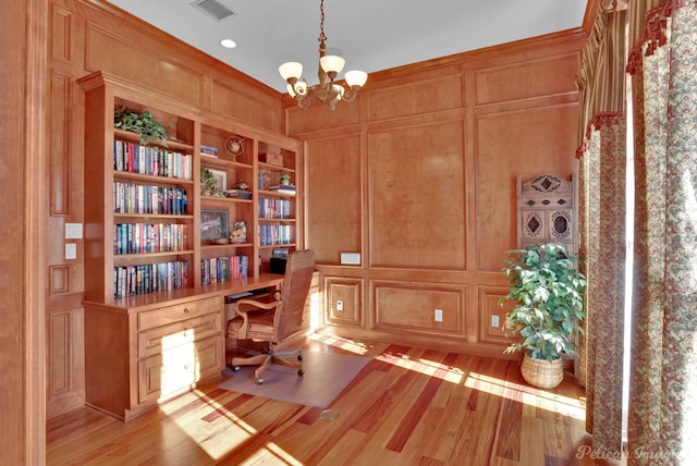 office space with built in desk, a notable chandelier, light hardwood / wood-style floors, and built in shelves