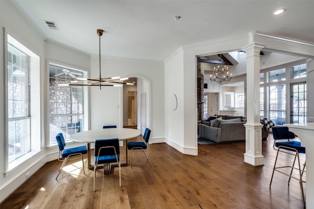 dining room with decorative columns, dark hardwood / wood-style floors, crown molding, and an inviting chandelier