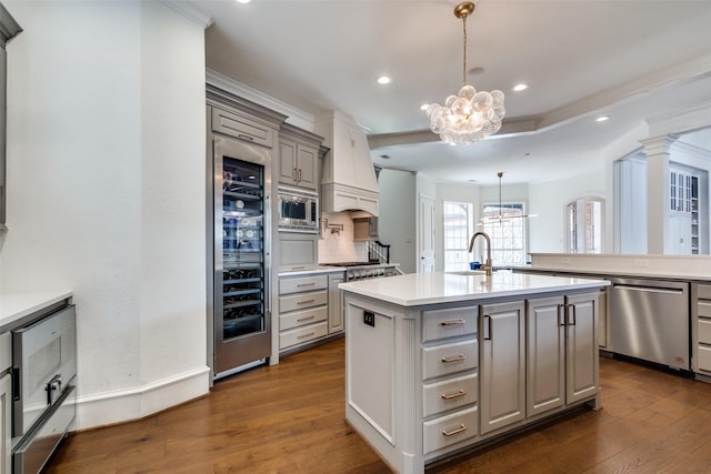 kitchen featuring stainless steel appliances, an inviting chandelier, sink, gray cabinets, and a kitchen island with sink