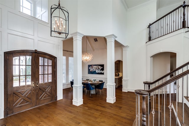 entryway with dark wood-type flooring, a high ceiling, a notable chandelier, and french doors