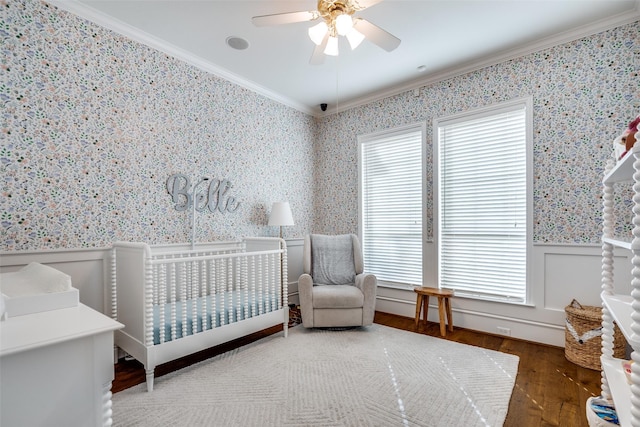 bedroom featuring ceiling fan, multiple windows, crown molding, and a crib