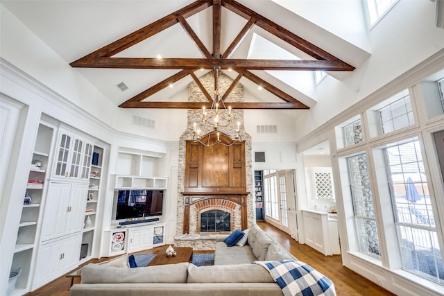 living room featuring high vaulted ceiling, built in shelves, a notable chandelier, and a fireplace