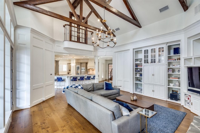 living room featuring high vaulted ceiling, decorative columns, beamed ceiling, and an inviting chandelier