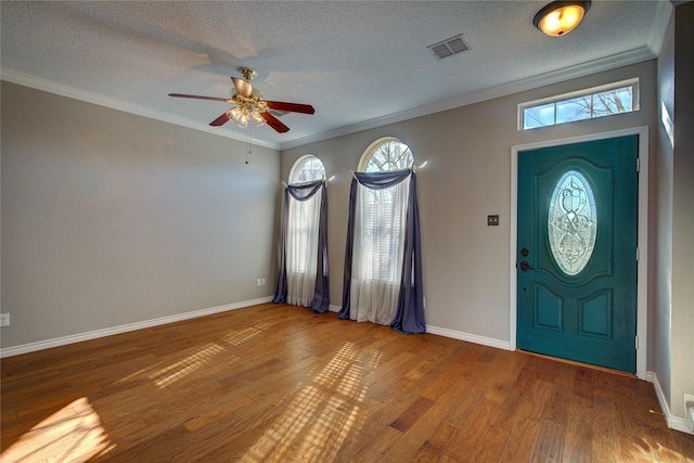 foyer entrance with a textured ceiling, ceiling fan, hardwood / wood-style flooring, and crown molding