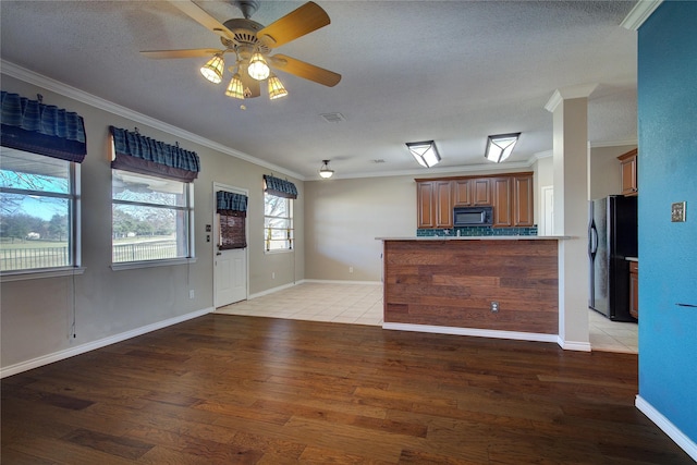 unfurnished living room with a textured ceiling, ceiling fan, light hardwood / wood-style floors, and crown molding