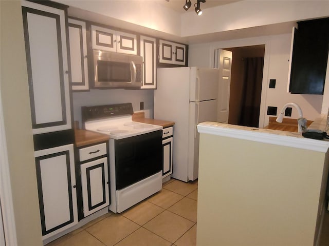 kitchen featuring light tile patterned flooring, white fridge, and electric range oven