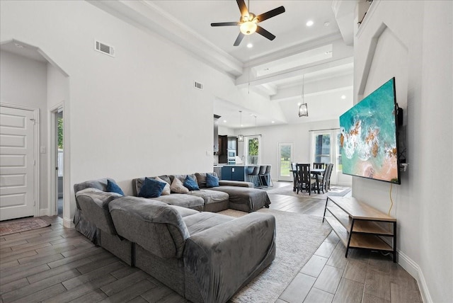 living room featuring ceiling fan and beamed ceiling