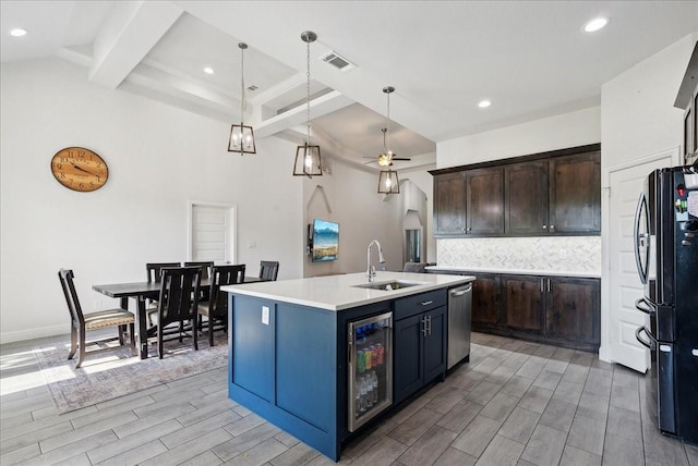 kitchen with sink, black fridge, a kitchen island with sink, pendant lighting, and wine cooler