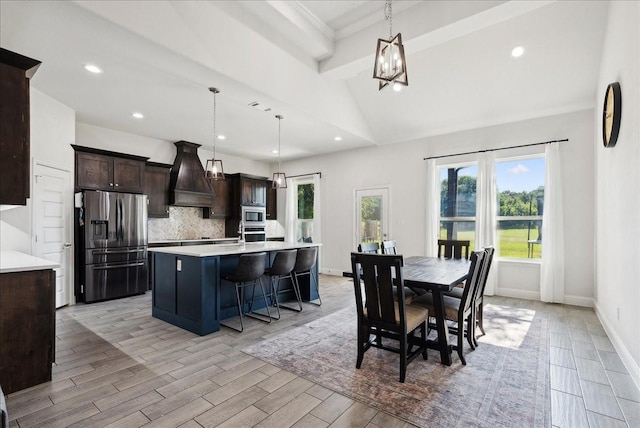 kitchen with custom exhaust hood, a kitchen island with sink, stainless steel appliances, decorative light fixtures, and backsplash