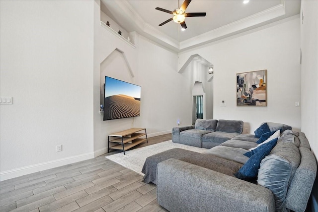 living room with a raised ceiling, ceiling fan, light hardwood / wood-style floors, and crown molding