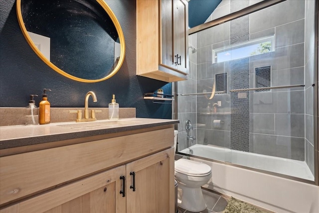 full bathroom featuring toilet, tile patterned floors, vanity, and bath / shower combo with glass door