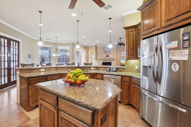 kitchen featuring ceiling fan with notable chandelier, appliances with stainless steel finishes, a center island, hanging light fixtures, and kitchen peninsula