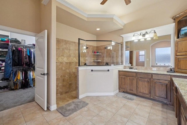 bathroom featuring a tile shower, ceiling fan, tile patterned flooring, crown molding, and vanity