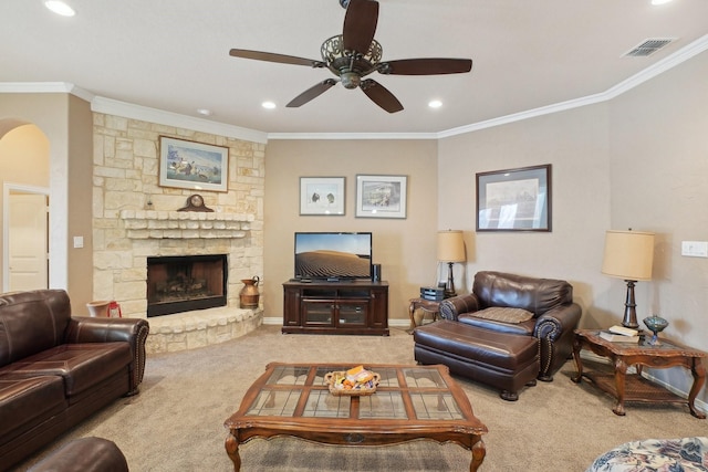 carpeted living room featuring ceiling fan, crown molding, and a fireplace