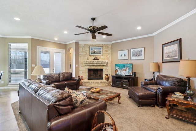 living room with ceiling fan, french doors, crown molding, and a stone fireplace