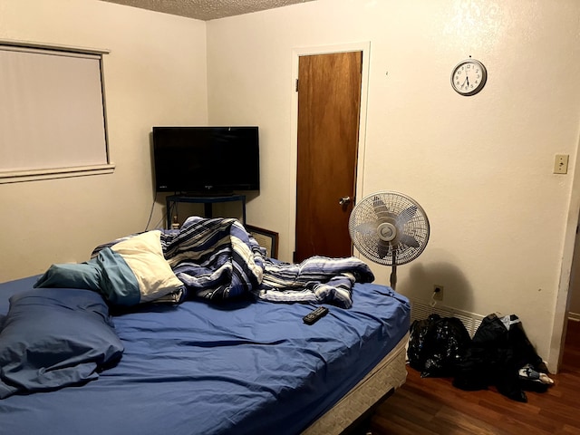 bedroom with a textured ceiling and dark hardwood / wood-style flooring