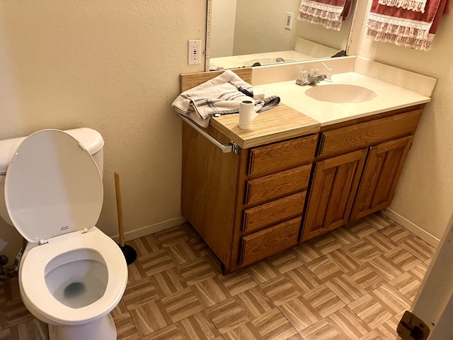 bathroom with toilet, vanity, and parquet floors