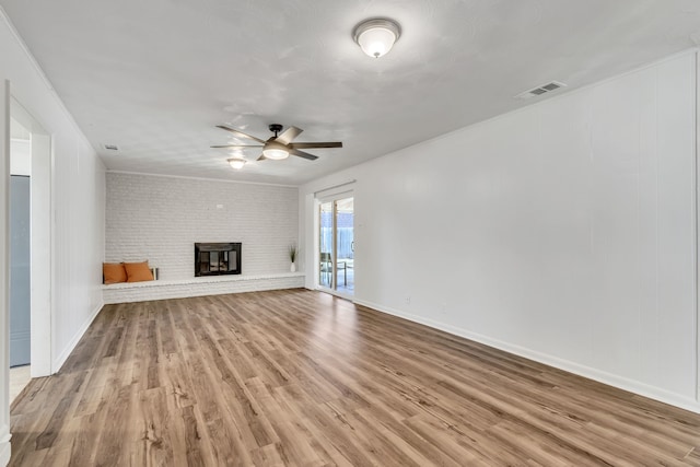 unfurnished living room with ceiling fan, hardwood / wood-style floors, a brick fireplace, and brick wall