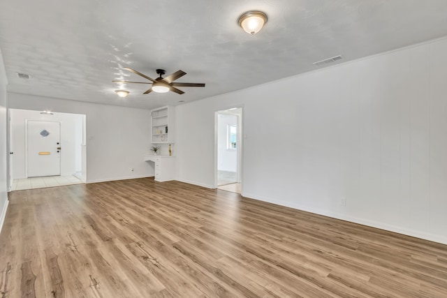 unfurnished living room featuring ceiling fan, light wood-type flooring, built in features, and a textured ceiling