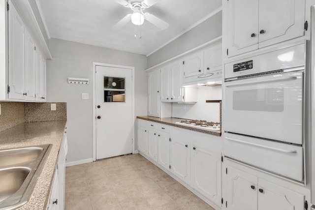 kitchen with white appliances, crown molding, ceiling fan, white cabinets, and sink