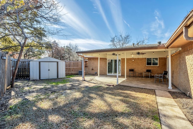 rear view of property featuring ceiling fan, a patio, and a storage shed