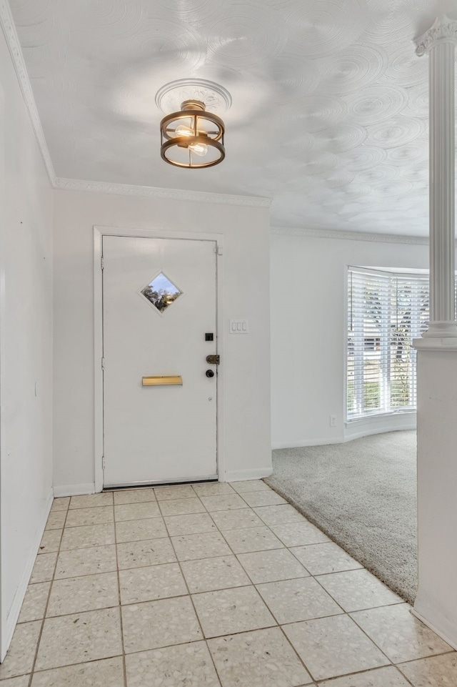 foyer entrance with light colored carpet, crown molding, and ornate columns