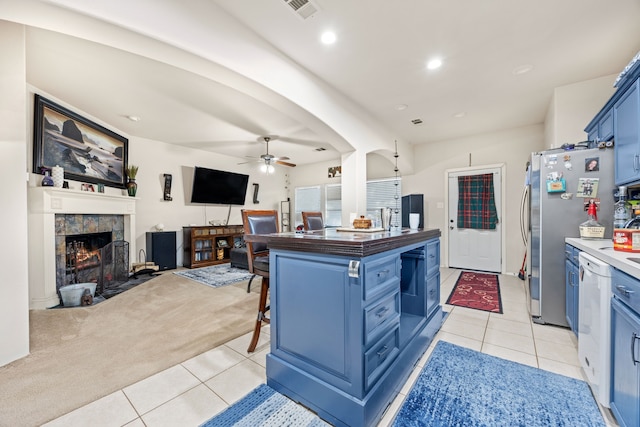 kitchen with stainless steel fridge, a kitchen breakfast bar, blue cabinets, and light tile patterned flooring