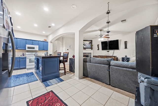 kitchen featuring white appliances, ceiling fan, light tile patterned floors, blue cabinetry, and backsplash