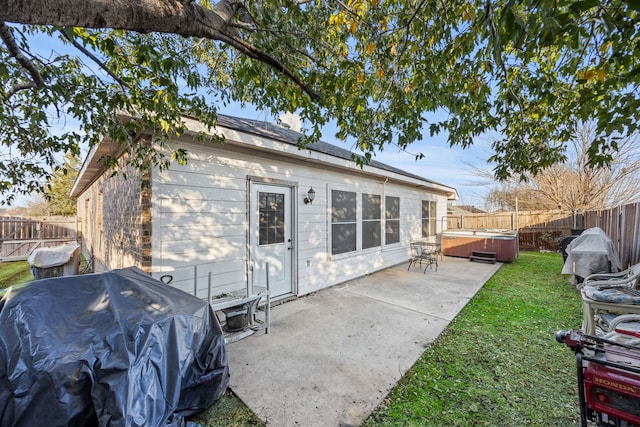 back of house with a lawn, a hot tub, and a patio area