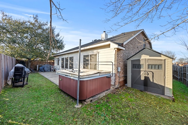 back of house with a patio, a yard, a hot tub, and a shed