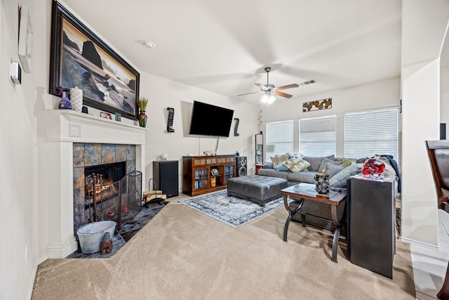 carpeted living room featuring a tiled fireplace and ceiling fan