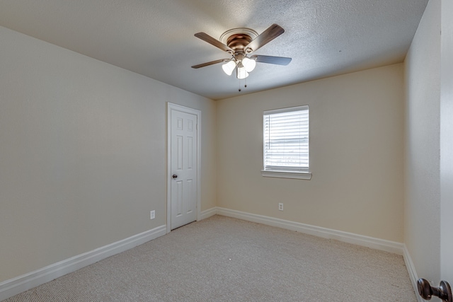 spare room with a textured ceiling, ceiling fan, and light carpet