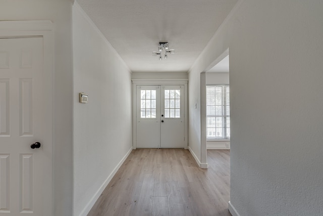 doorway featuring french doors, a chandelier, light wood-type flooring, and a textured ceiling