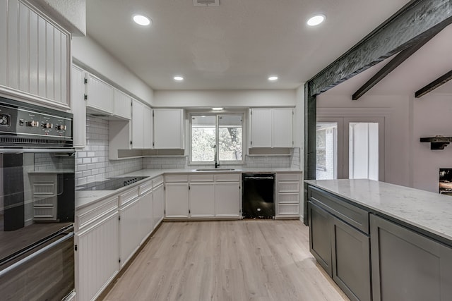 kitchen with light stone counters, white cabinets, light hardwood / wood-style floors, and black appliances