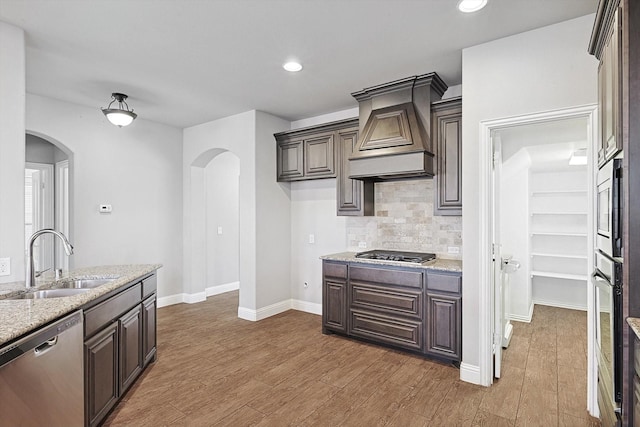 kitchen with stainless steel appliances, dark hardwood / wood-style floors, custom exhaust hood, and sink