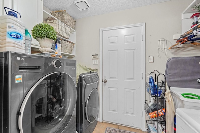 laundry area with washer and dryer, a textured ceiling, and light tile patterned floors