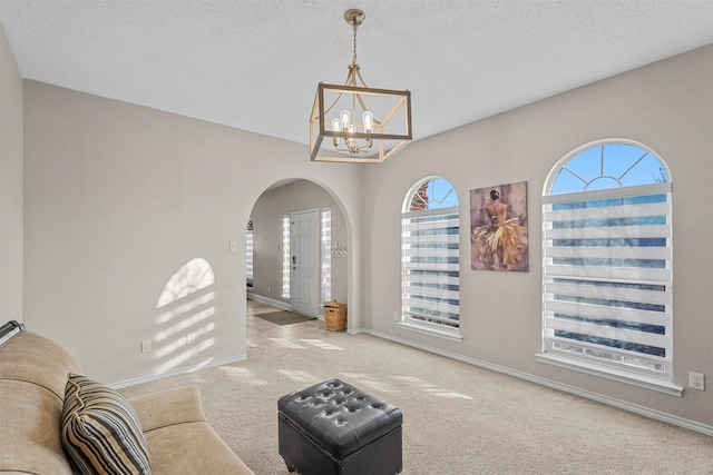 interior space with a textured ceiling, a chandelier, and carpet