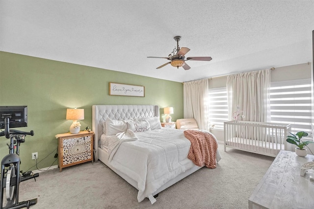 bedroom with ceiling fan, light colored carpet, and a textured ceiling