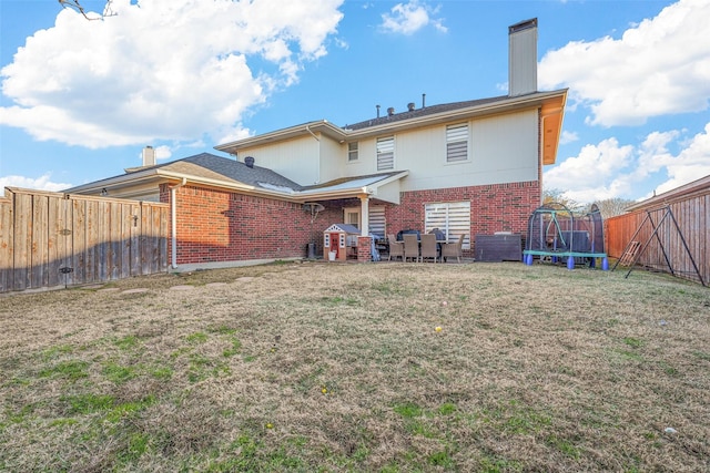 rear view of house with a lawn and a trampoline