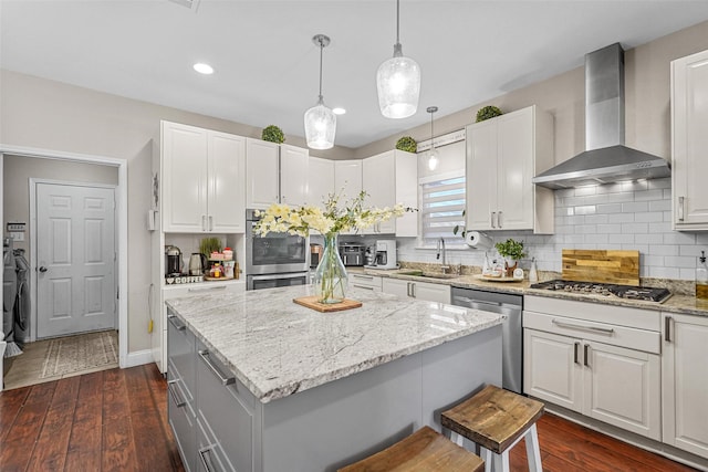 kitchen with stainless steel appliances, dark wood-type flooring, wall chimney exhaust hood, white cabinets, and sink