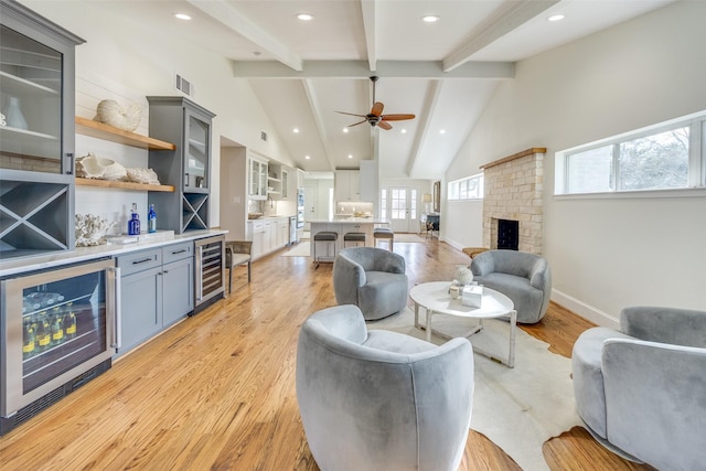 living room with ceiling fan, light wood-type flooring, a fireplace, and wine cooler