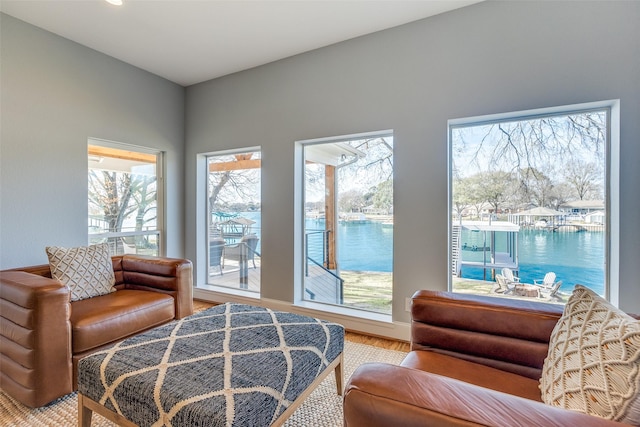 sitting room with light wood-type flooring and a water view