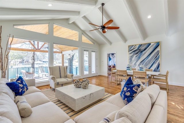 living room featuring ceiling fan, vaulted ceiling with beams, a wealth of natural light, and light hardwood / wood-style floors