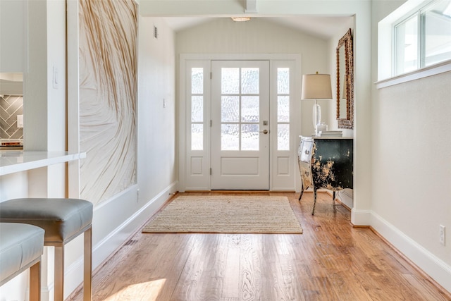 doorway featuring light wood-type flooring and vaulted ceiling