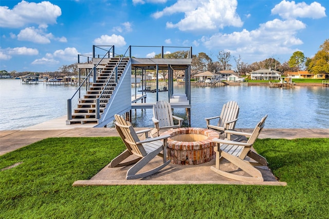 dock area with a lawn, a fire pit, and a water view