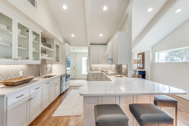 kitchen with sink, a kitchen bar, lofted ceiling, and kitchen peninsula