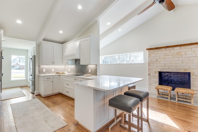 kitchen with a kitchen breakfast bar, stainless steel fridge, white cabinetry, and beam ceiling