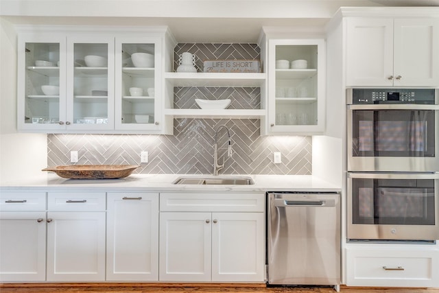 kitchen with sink, stainless steel appliances, white cabinets, and backsplash